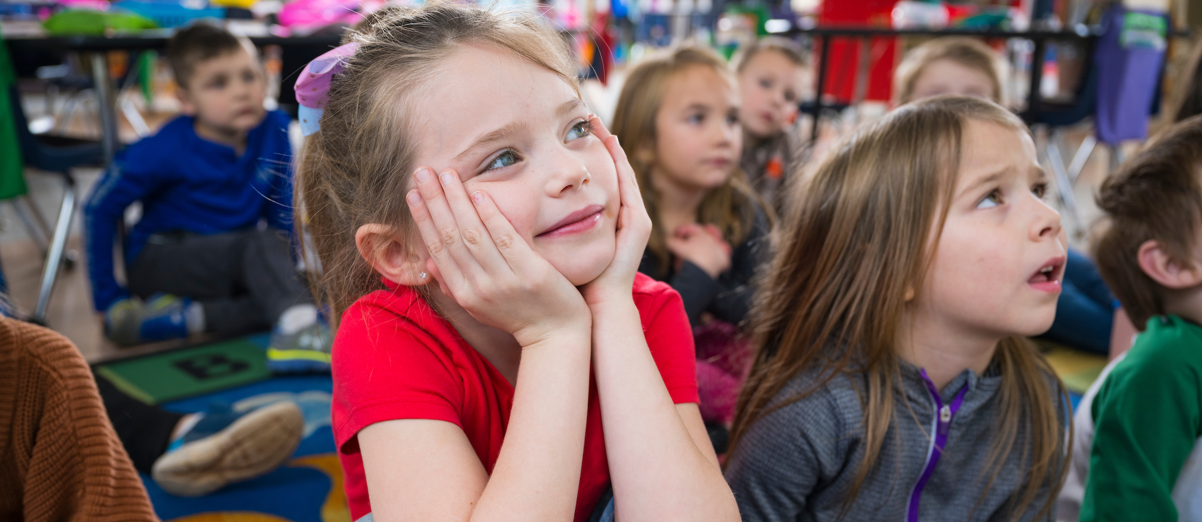 A student smiles at the camera in a classroom with students in the background