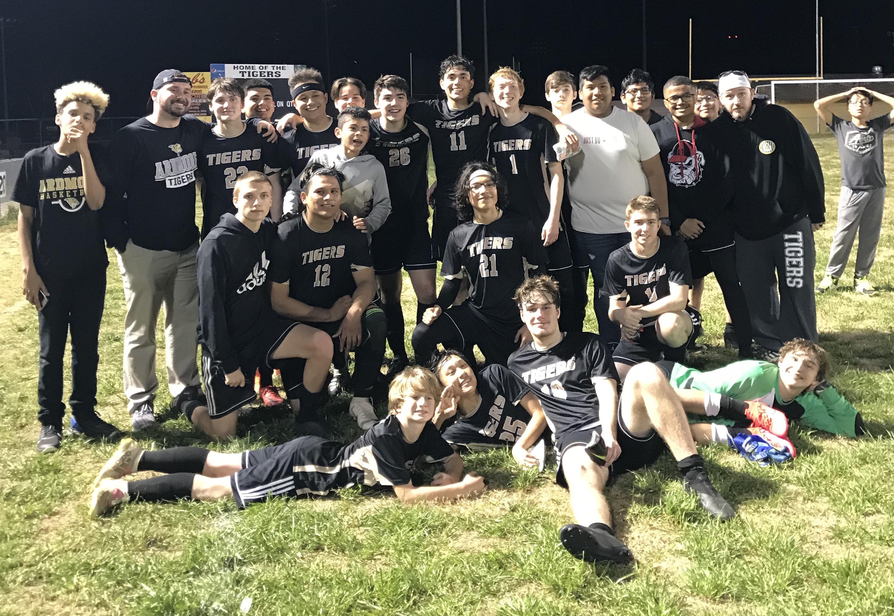 Group photo of soccer team relaxing on the soccer field after a game