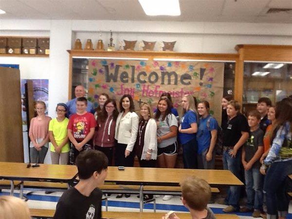 state school superintendent with group of teachers in front of welcome sign