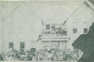 students sitting in front of and on the roof of the First Roff School