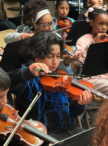 Student playing violin in band concert