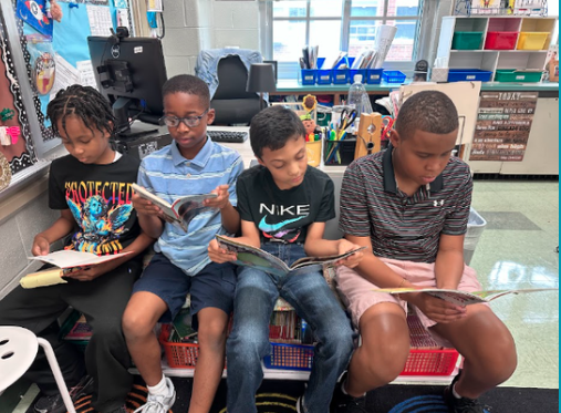four boys sitting and reading