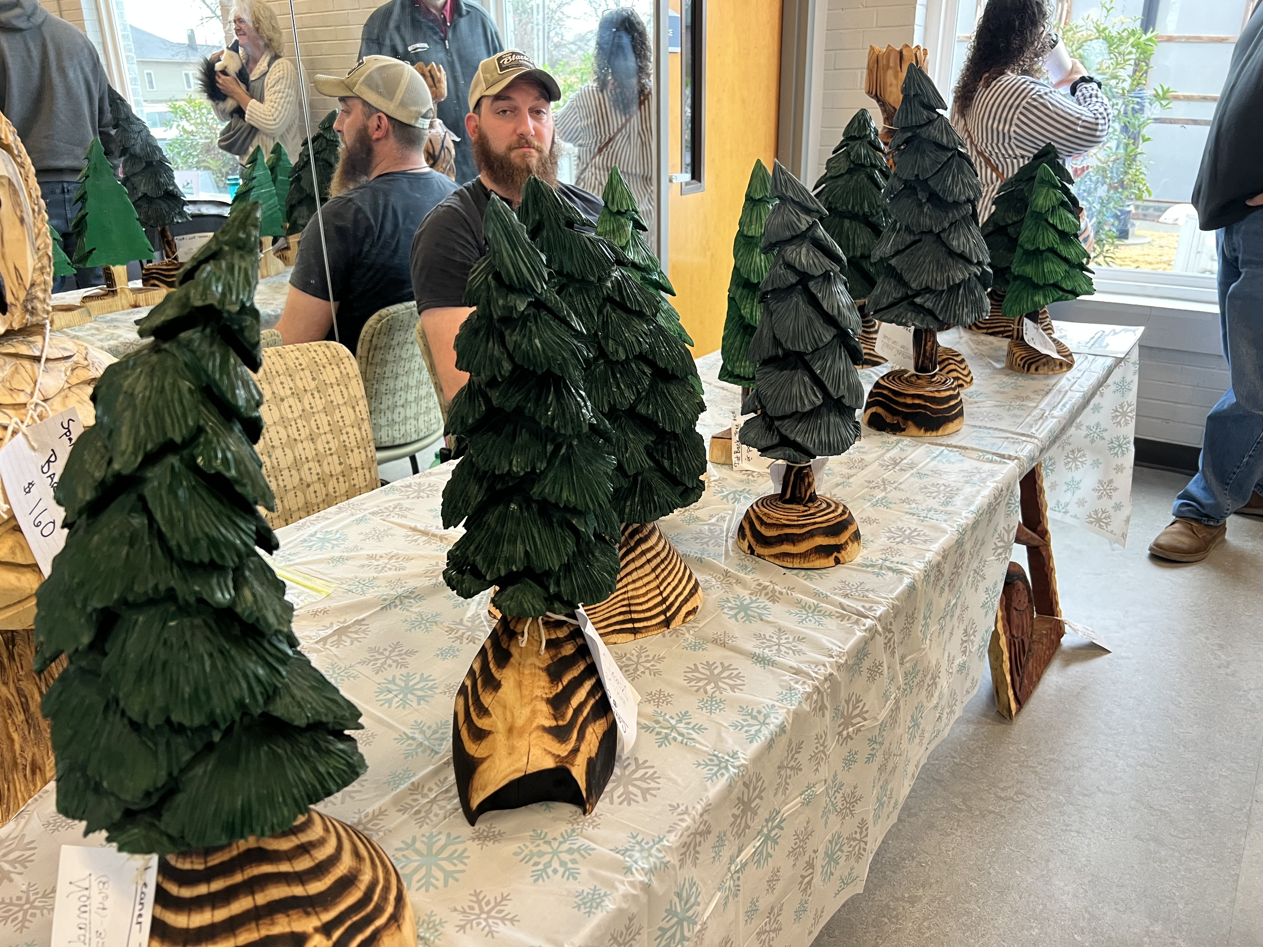 a table with 2ft tall carved wooden christmas trees