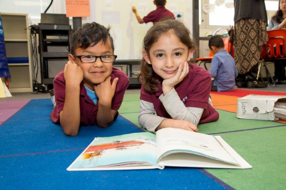 Two kids reading a book on the floor