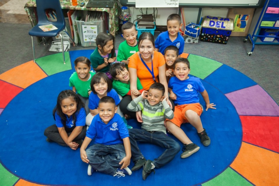 Kids and teacher sitting on a colorful mat.