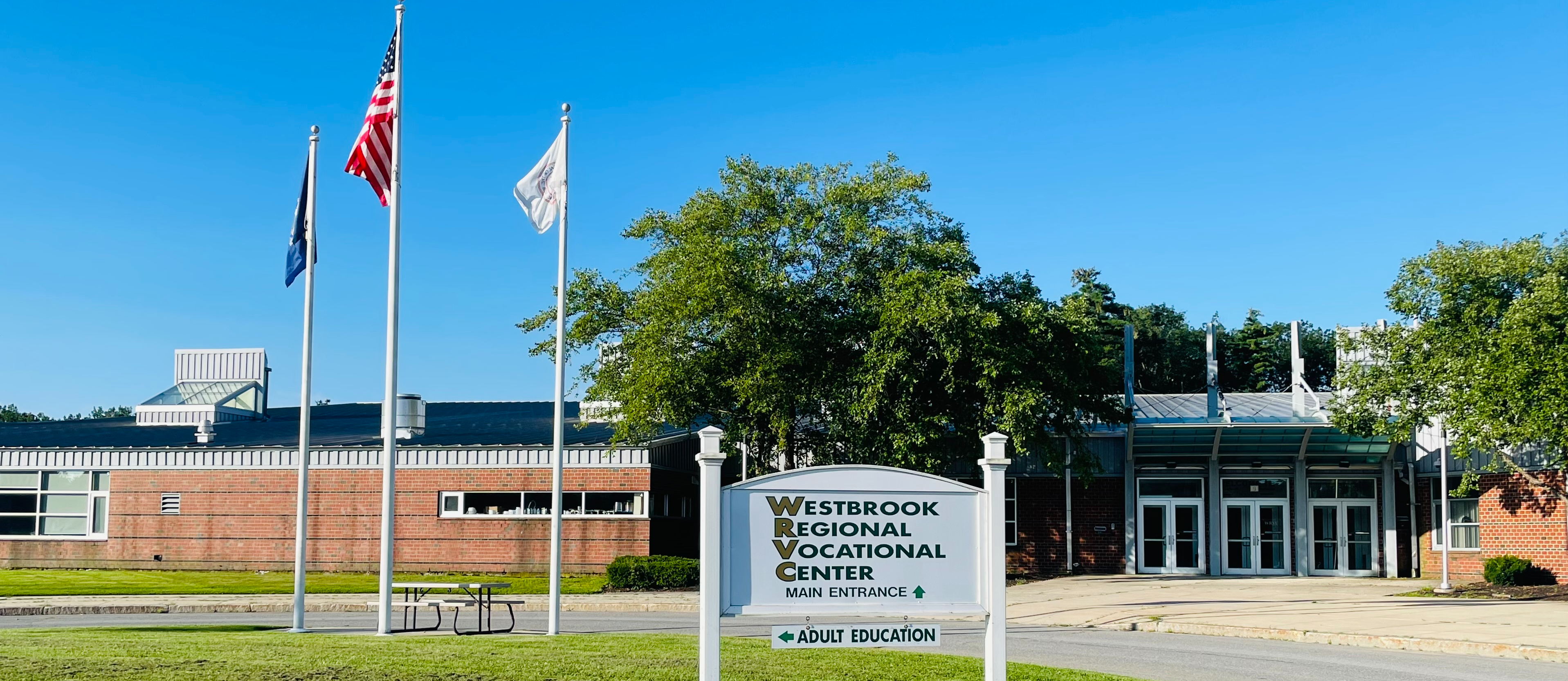 image of front of westbrook regional vocational center building bus circle area with flagpoles
