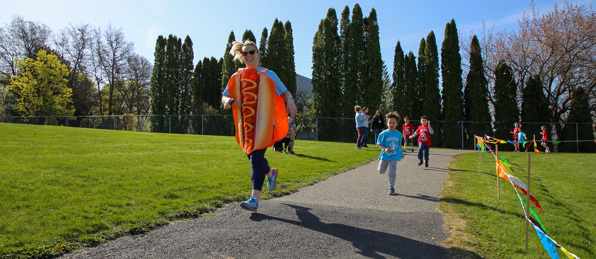 teacher in hot dog costume running with kids
