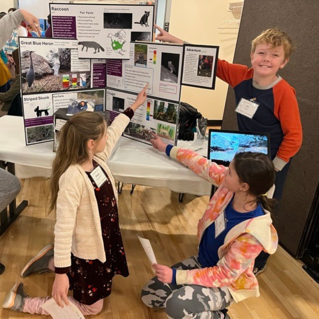 Three students presenting in front of a poster board