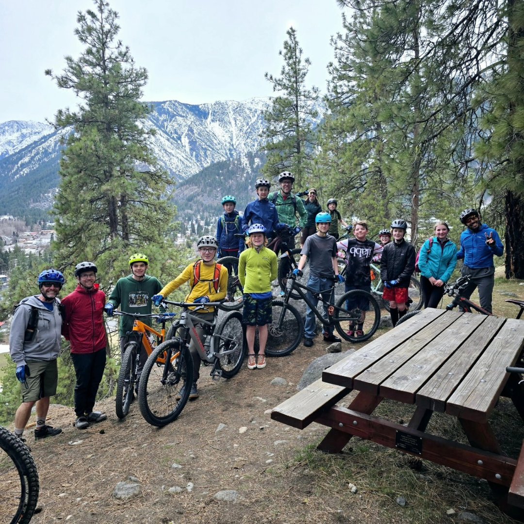 Group of students standing next to mountain bikes on top of a mountain