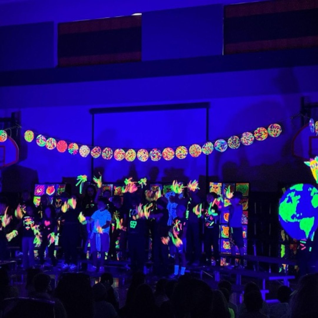 Students standing in a line in a dark room with glow in the dark  hand prints