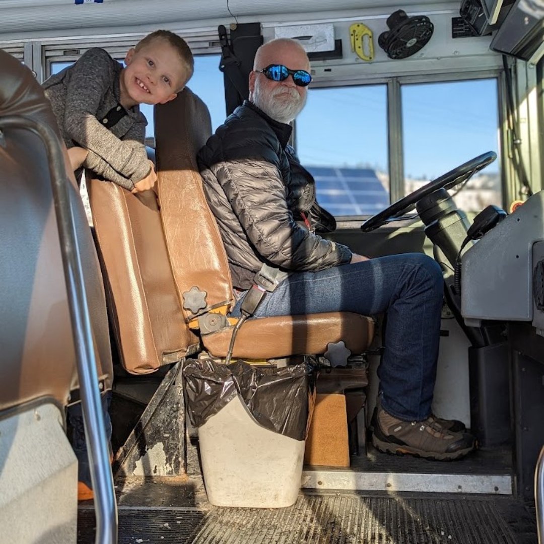 A student standing next to bus driver in the school bus