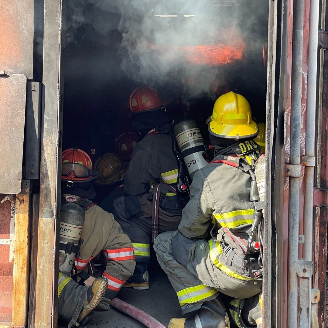 Students in fire gear putting fire out in fire fighting program