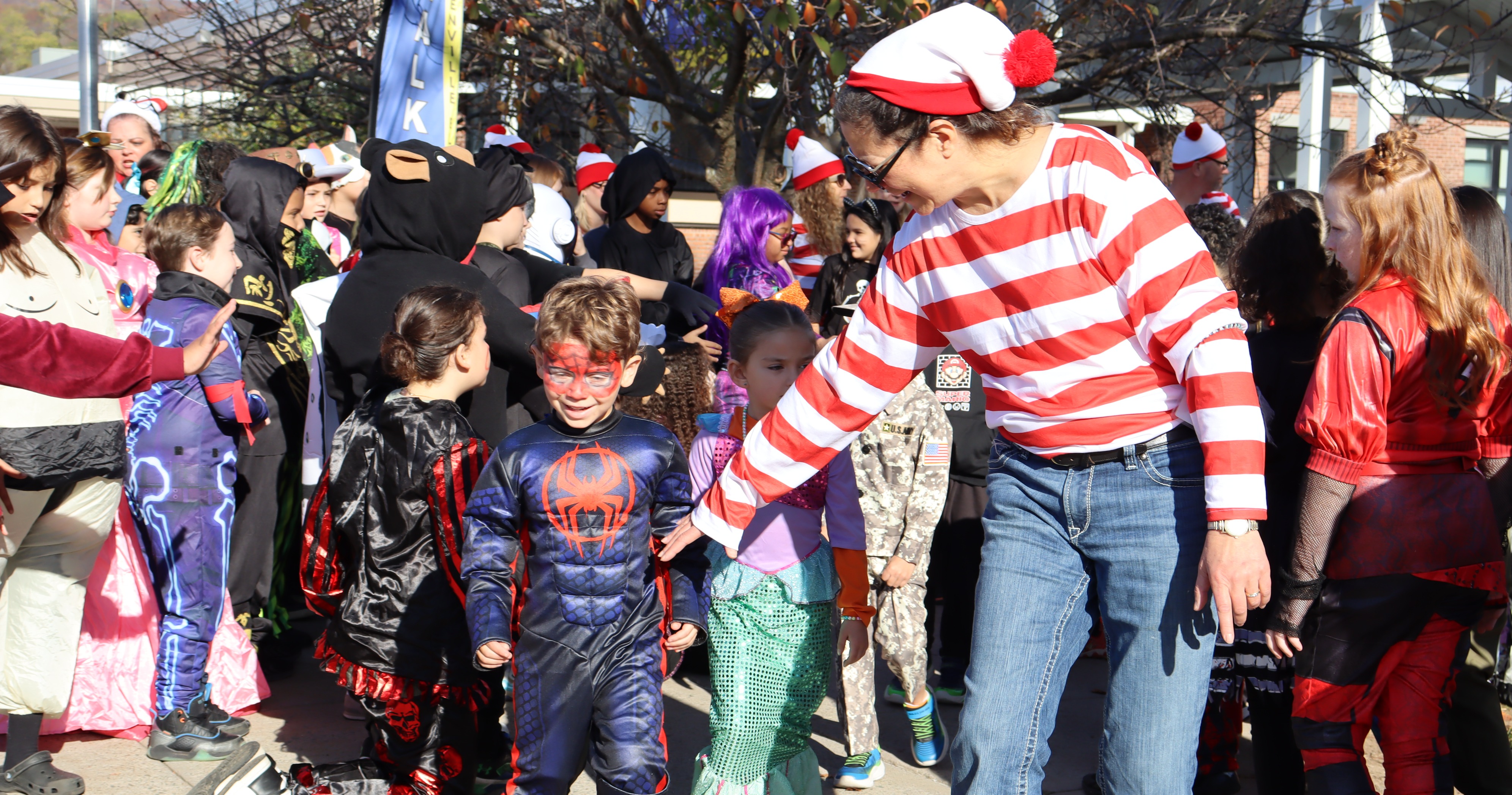 A teacher leads a student in a Halloween parade