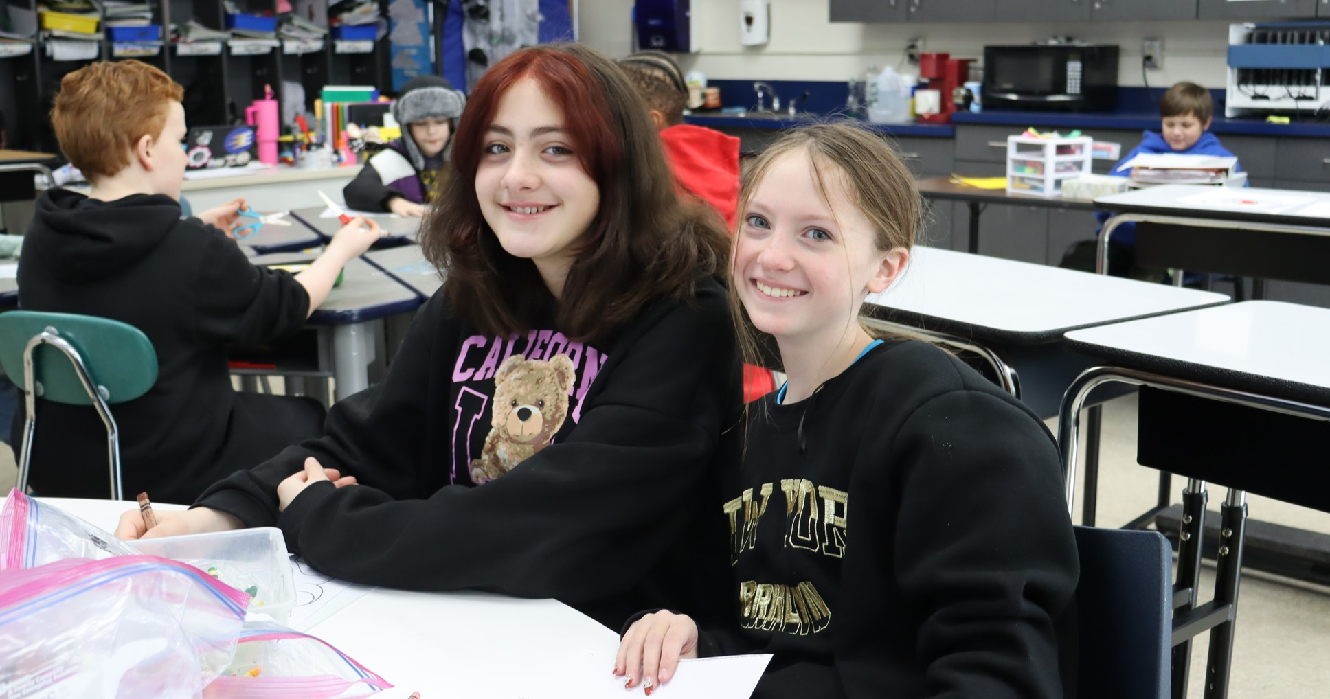 Two students sitting at a desk and smiling