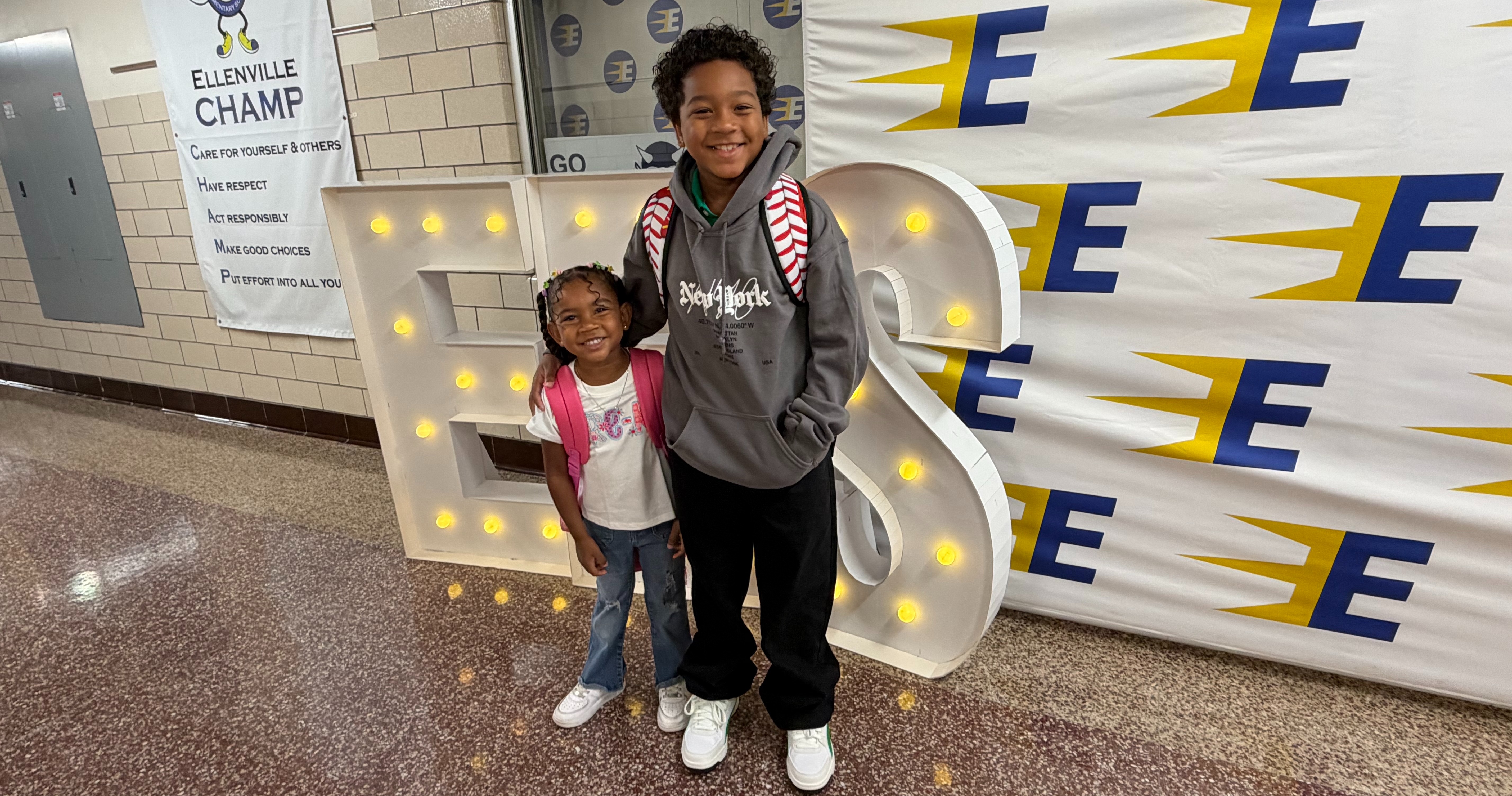 Two students posing in front of an Ellenville sign