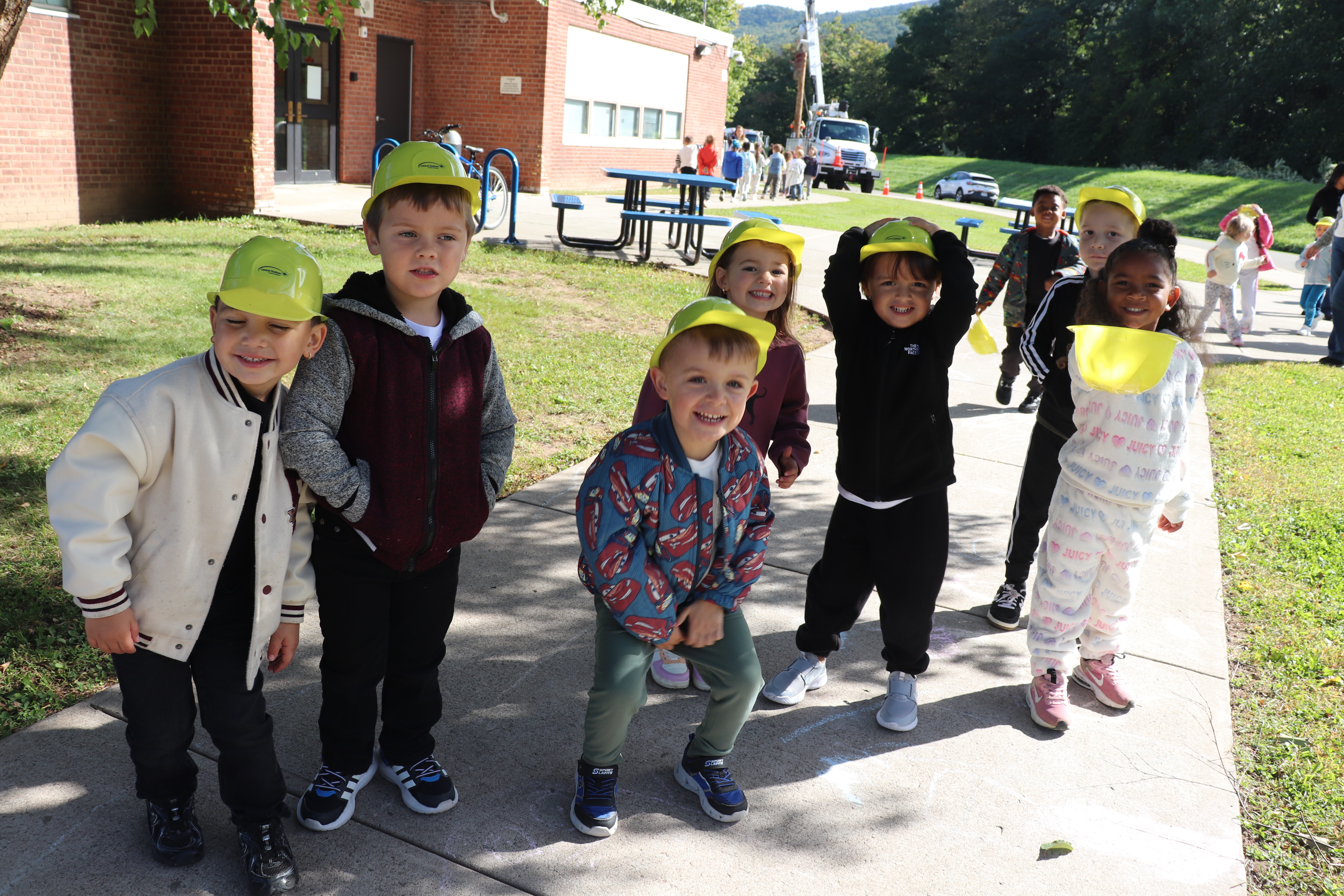 A group of young students wearing yellow plastic construction hats