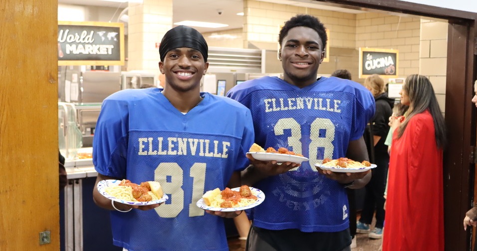 Two football players holding plates of spaghetti