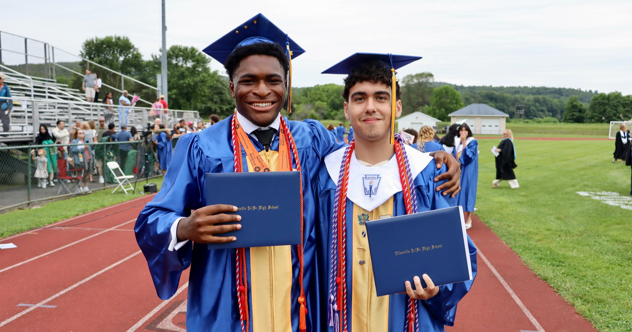 Two graduates holding diplomas