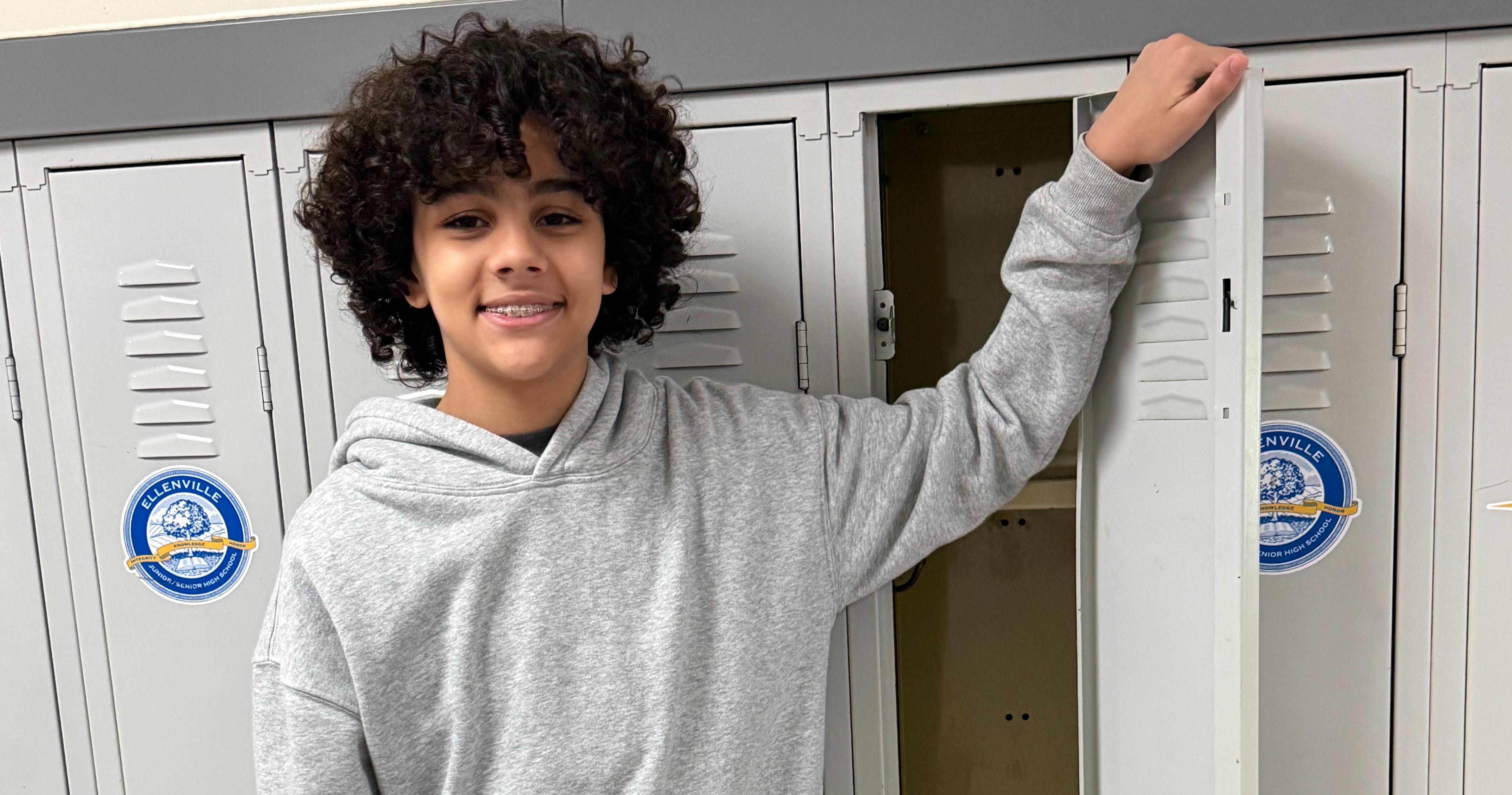 A student stands at his open locker