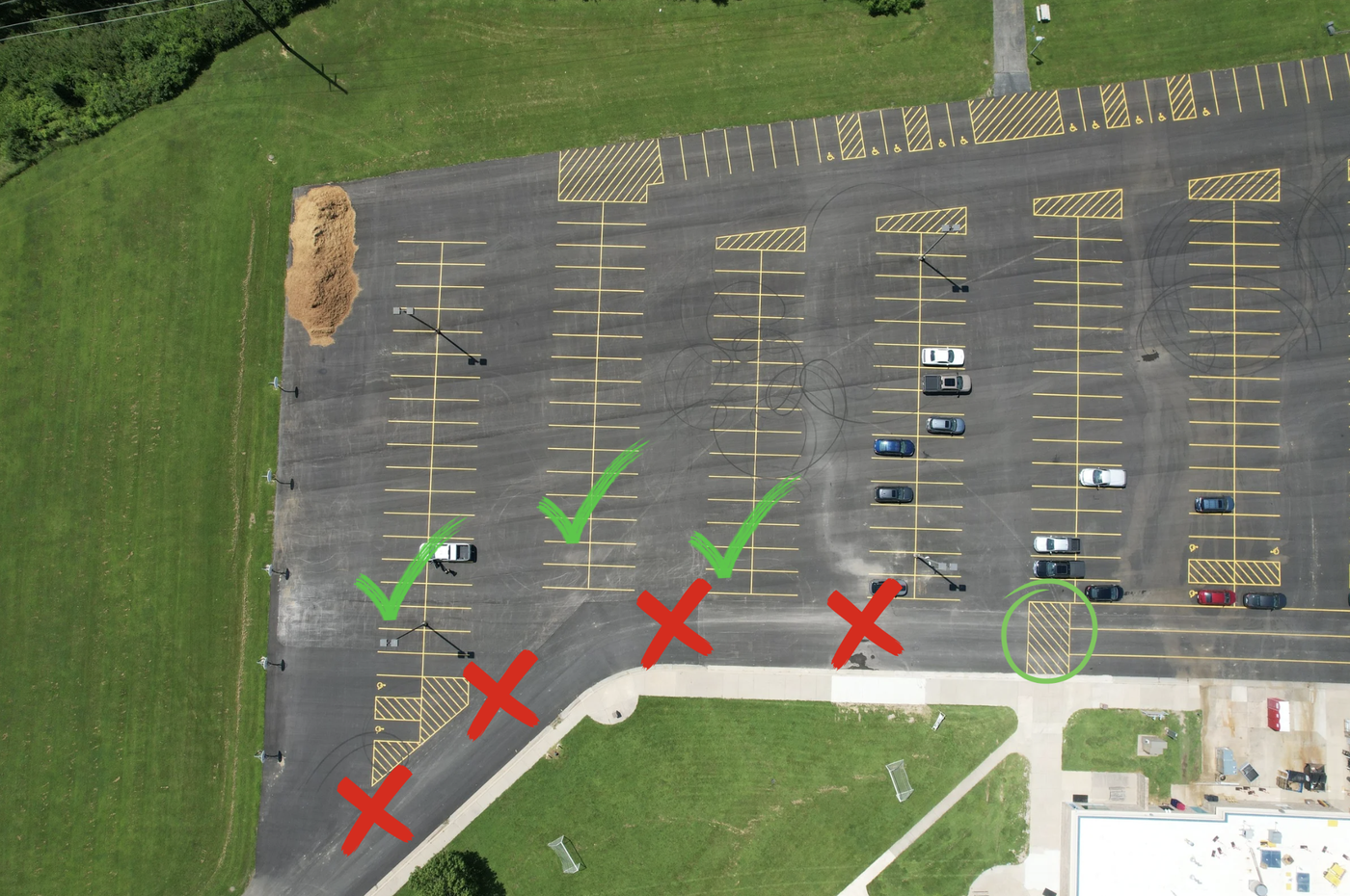 Photograph depicting the back parking lot at AES with green checkmarks indicating safe areas to park and walk students into the building at morning arrival time.