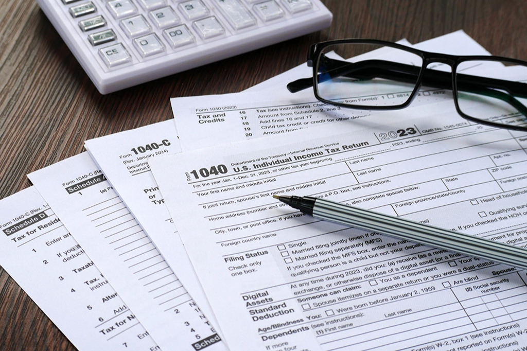 Tax documents with calculator, glasses, and pen