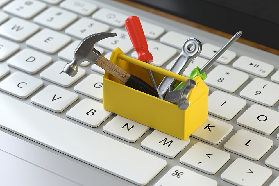 Pins in a A tiny toolbox with tools sitting on top of a white keyboard