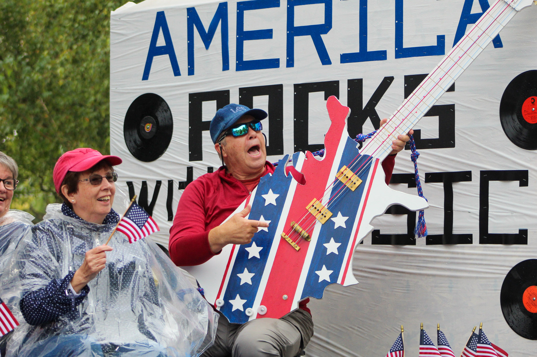 Class of 1969 float with man holding a big red, white, and blue guitar prop