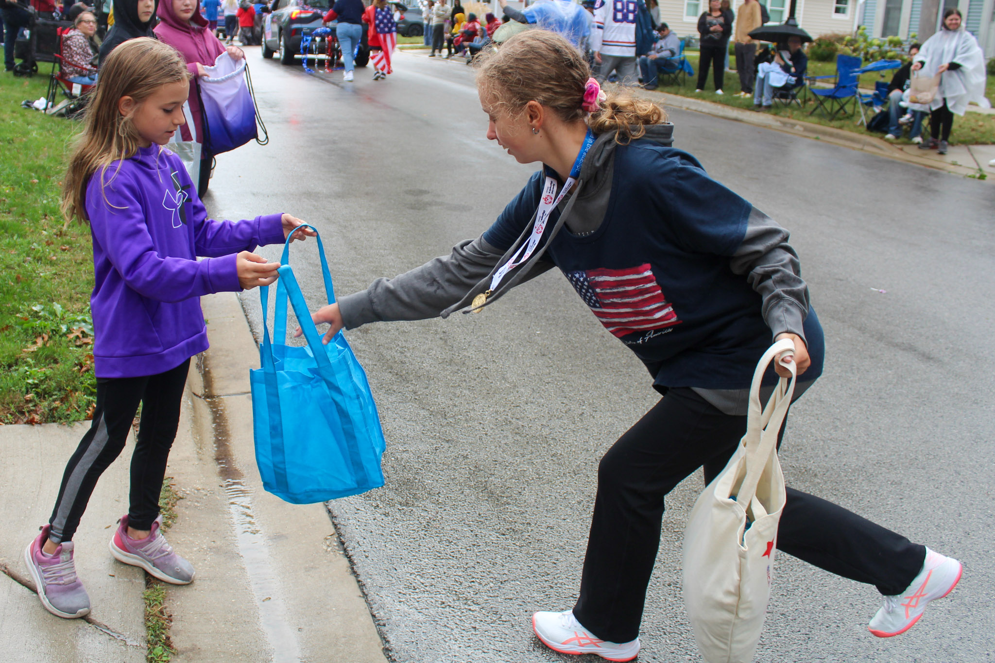 Special Olympic student hands candy to girl on side of street