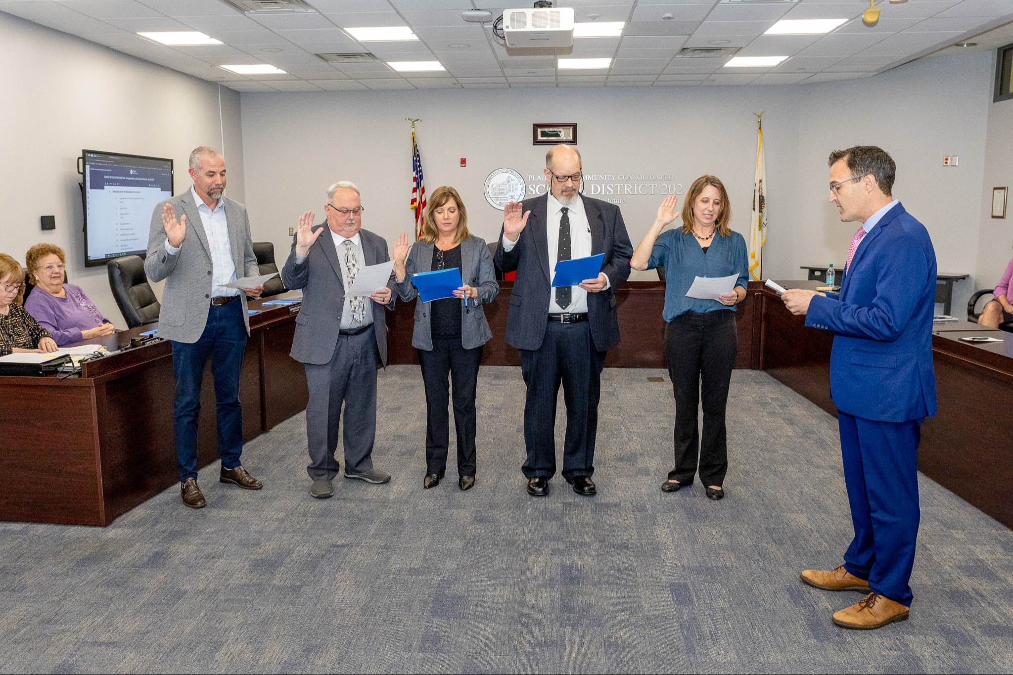 five adults with raised right hands taking the oath of office