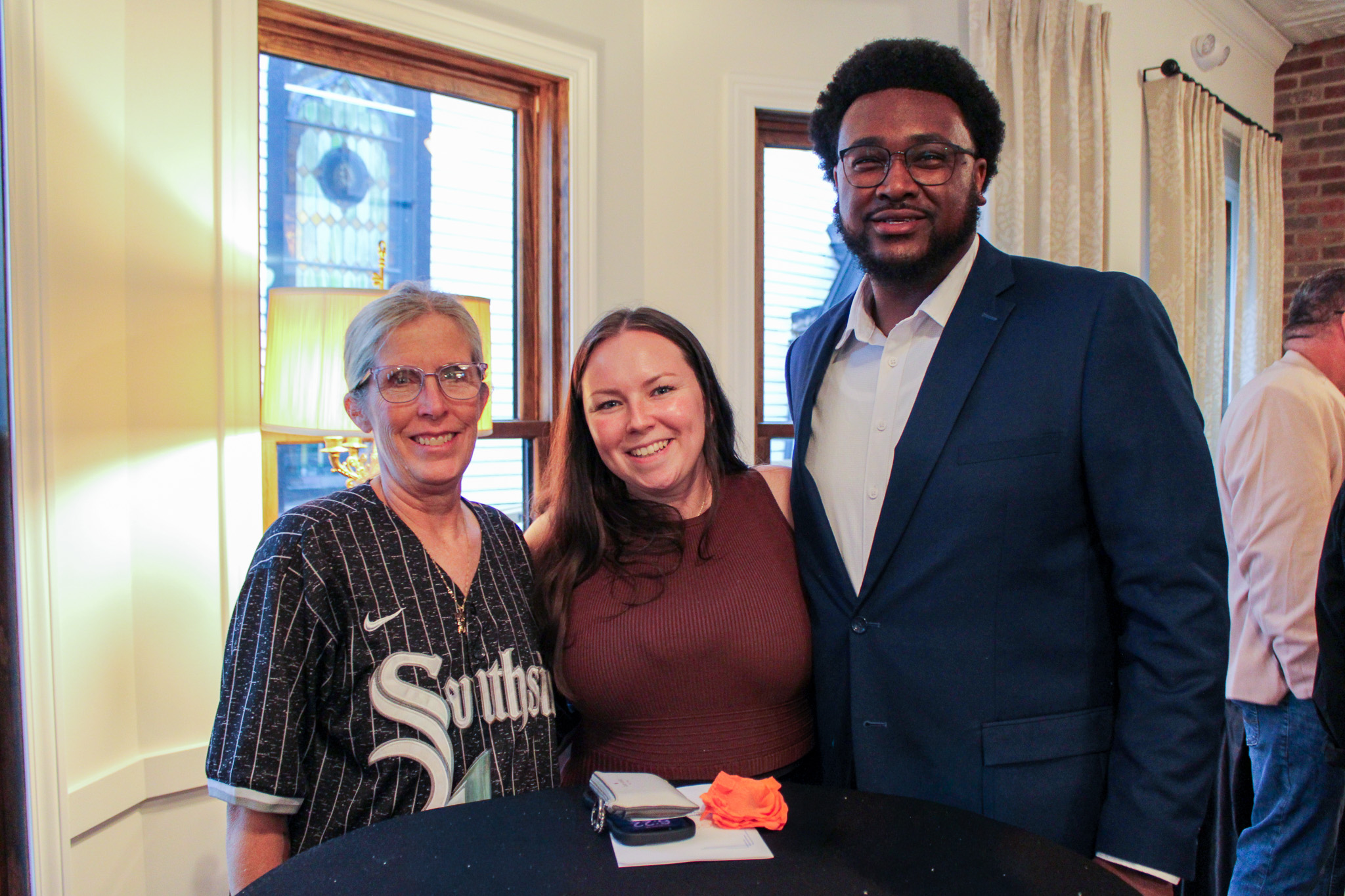 two women and a man stand behind a high top table