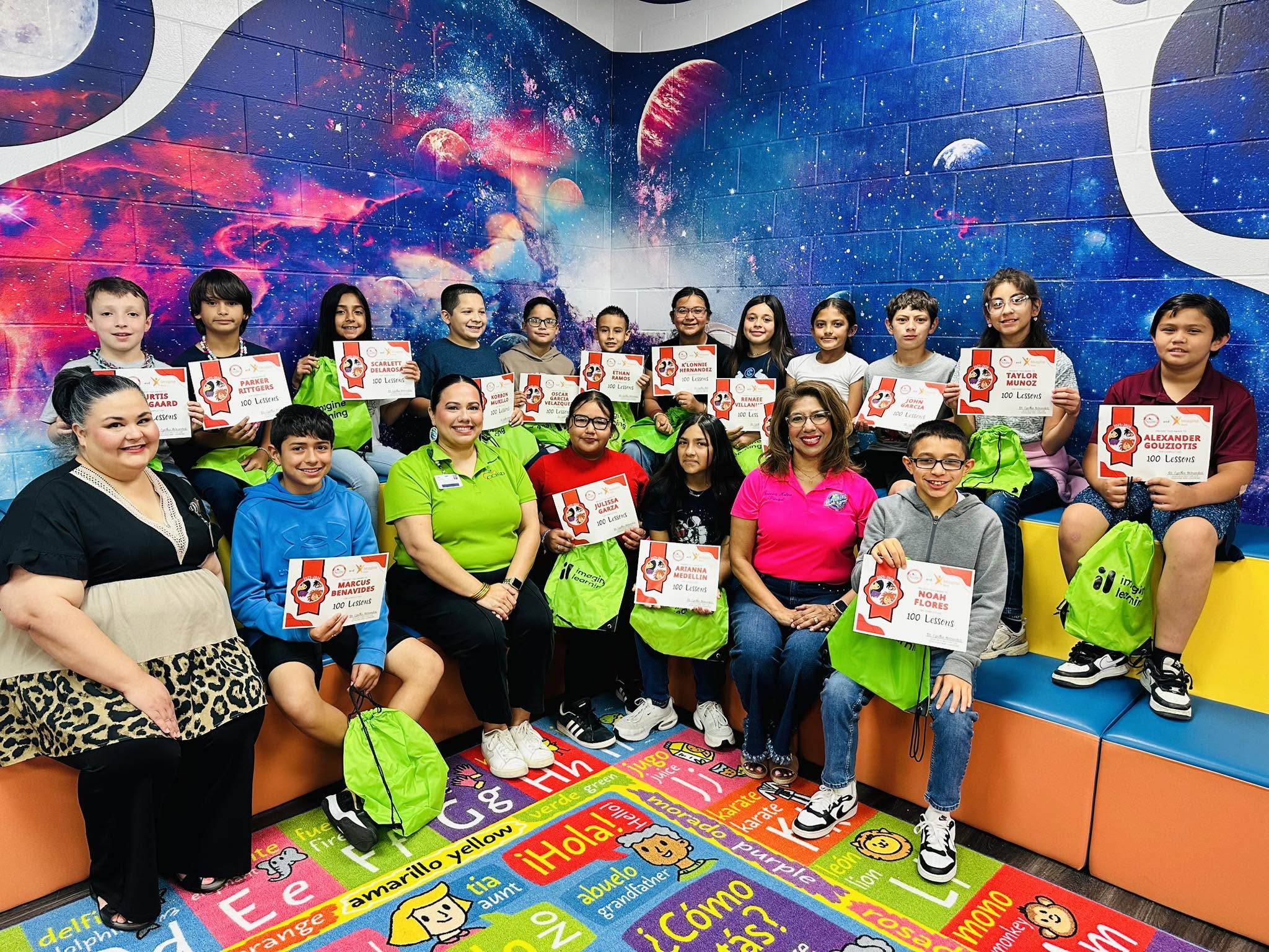 Group of people in a room with a space theme, holding certificates and smiling.