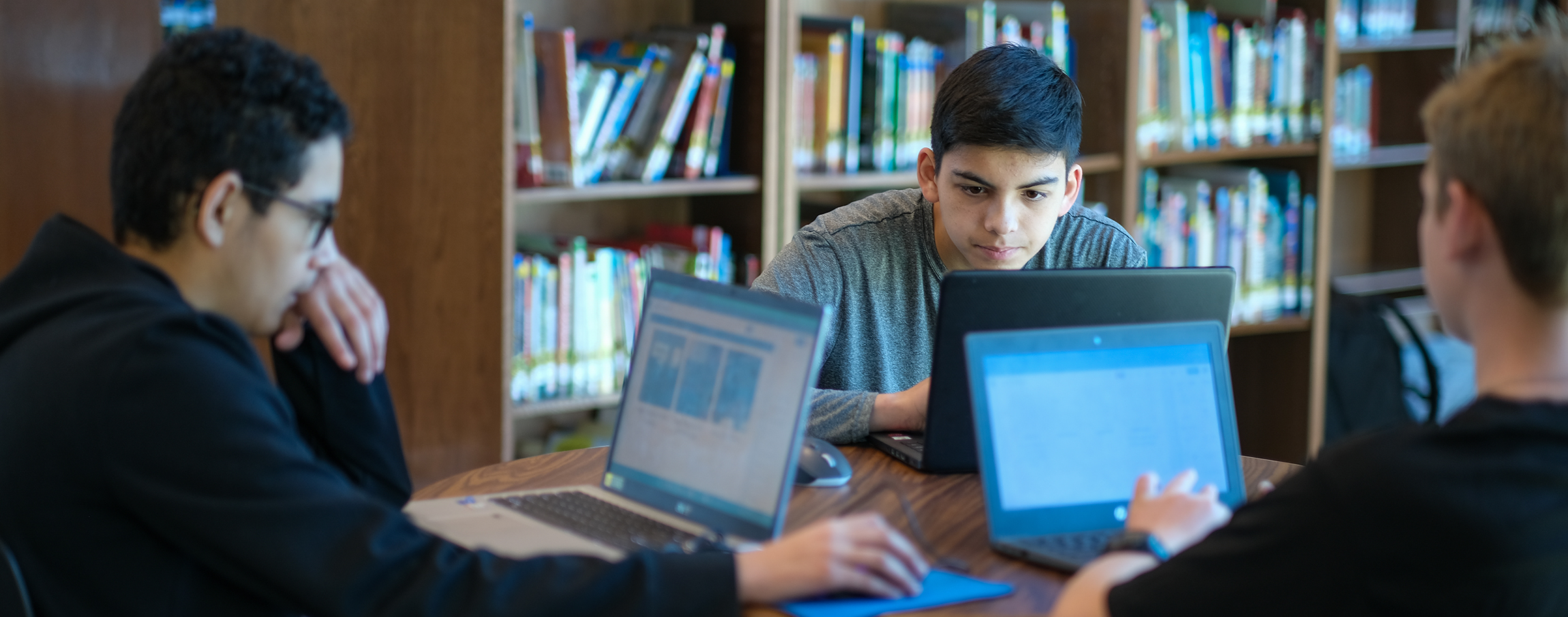 Three student on computers in the library 