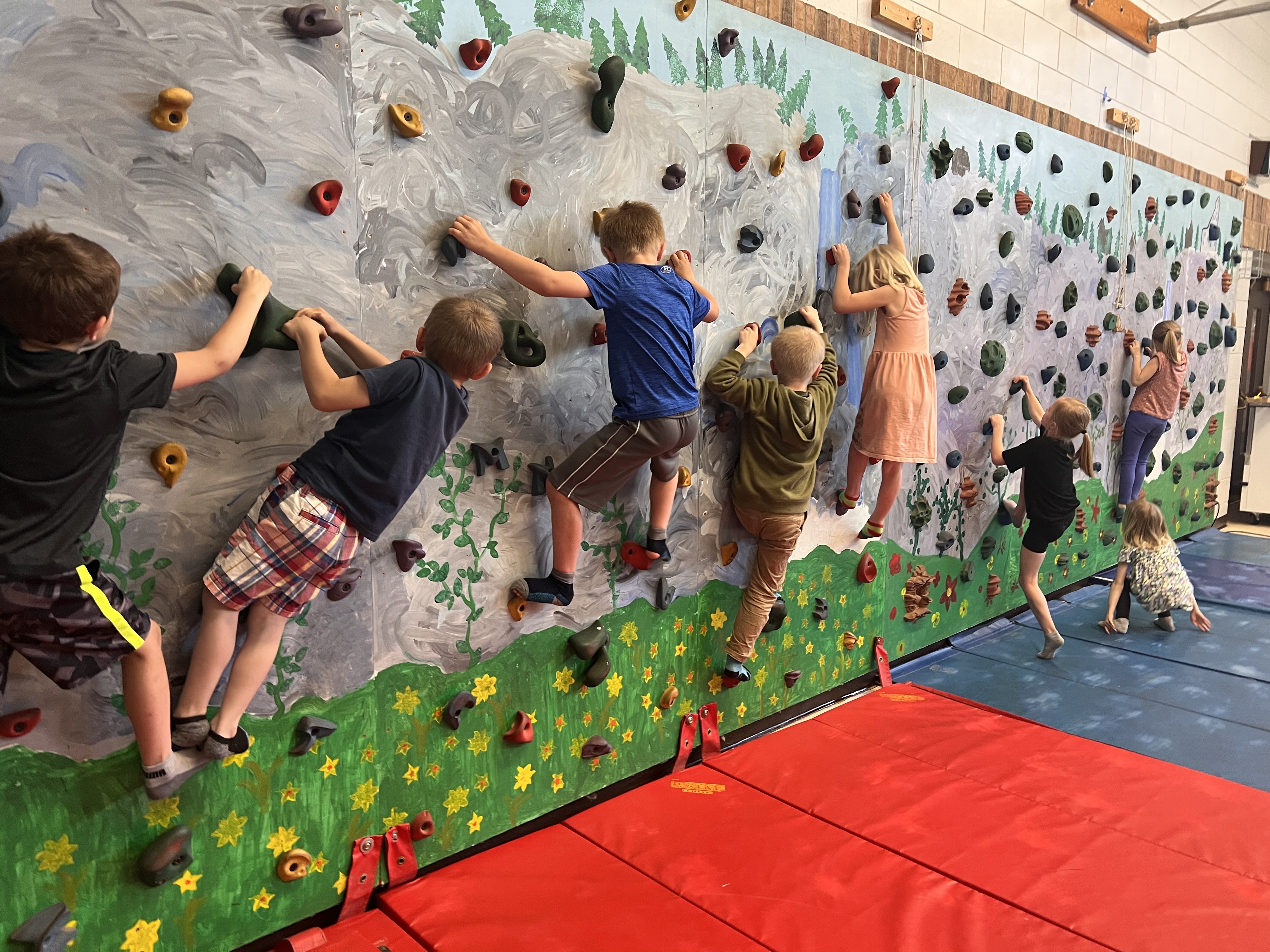 Children climbing on a bouldering wall.