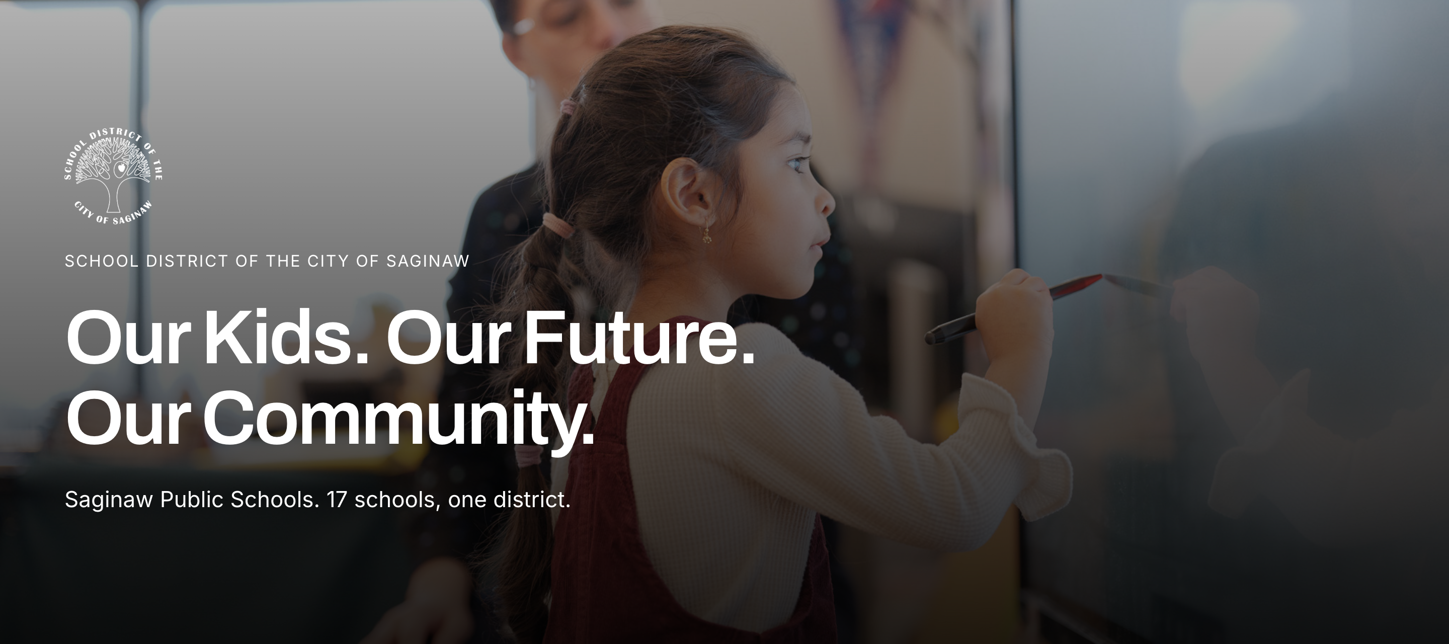 A young girl writes on a whiteboard, with an adult behind her. Text reads "Our Kids. Our Future. Our Community."