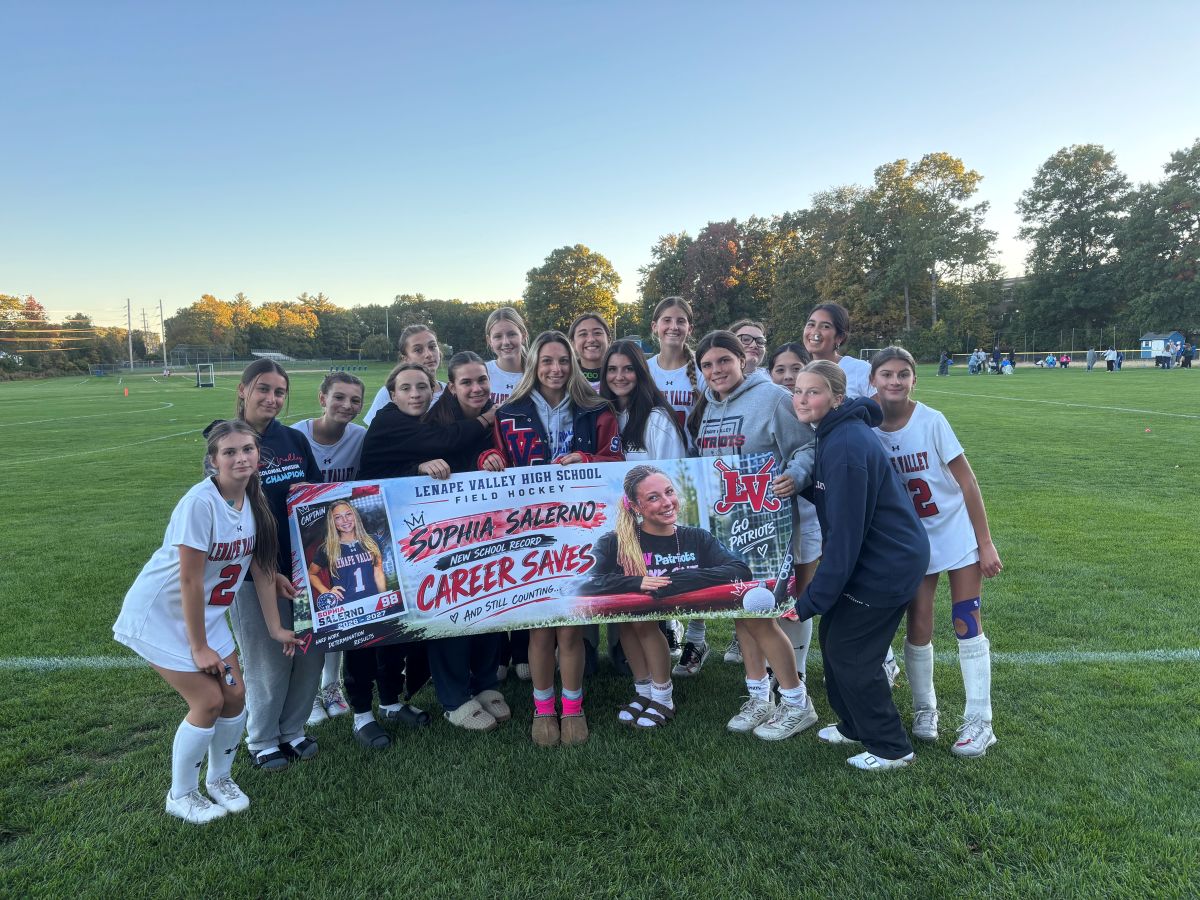 Lenape Valley field hockey goalie Sophia Salerno celebrates with teammates after breaking the school record for career saves. The team holds a banner honoring Sophia’s achievement, which reads “Sophia Salerno — Career Saves — New School Record.” Sophia reached 538 career saves after recording 27 saves in the game.