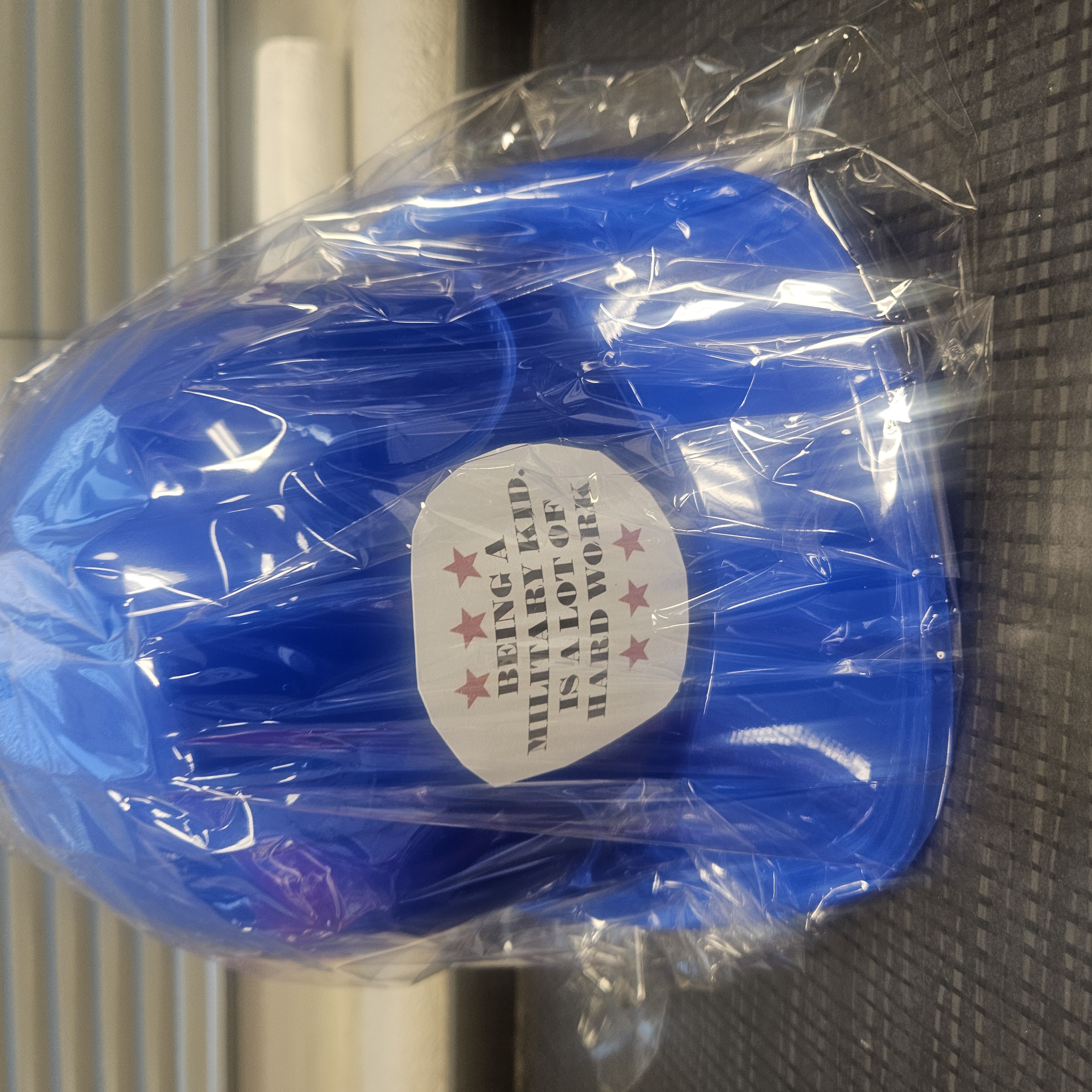 Picture of a hard hat with text that says being a military kid is hard work