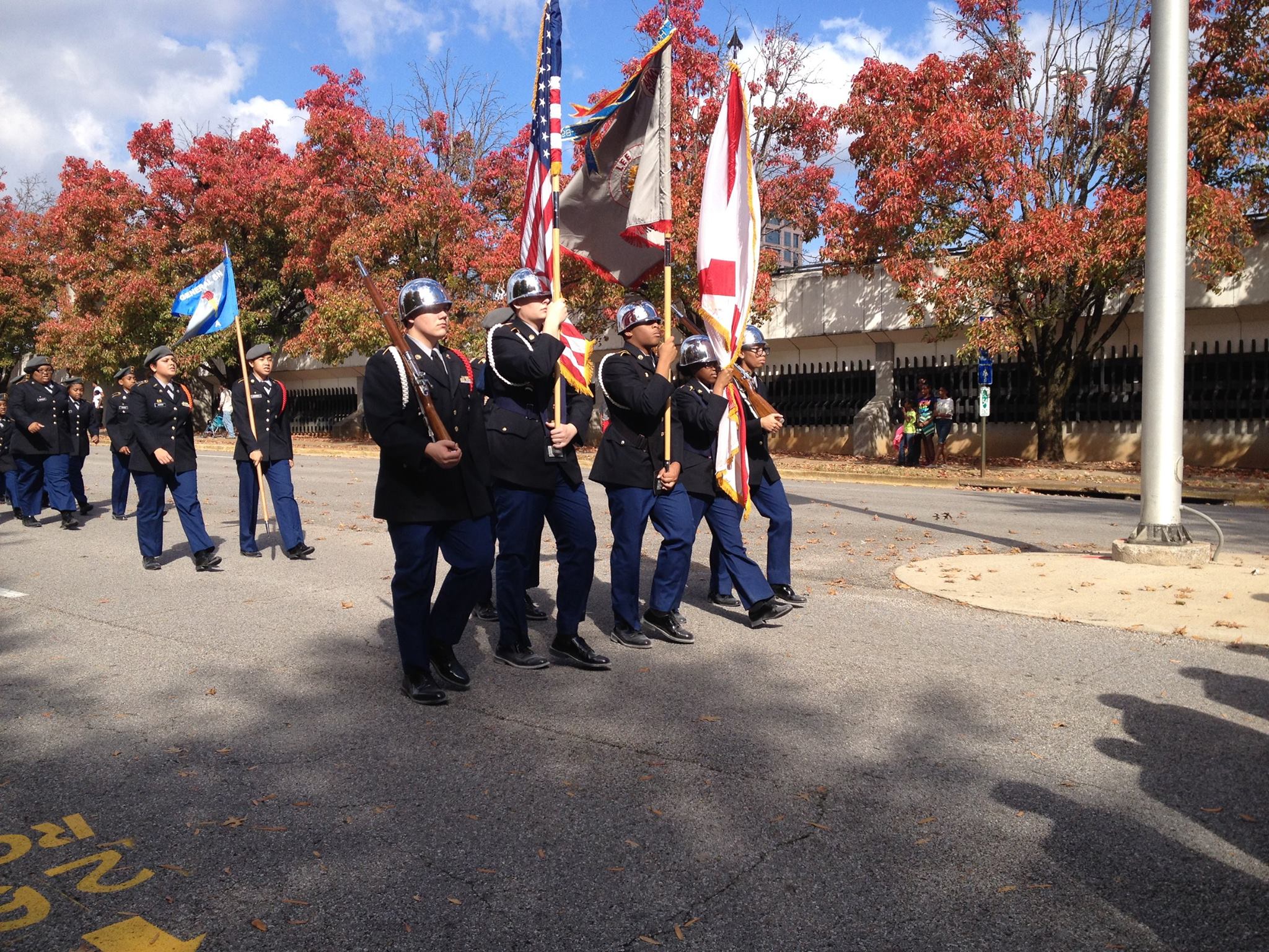 Four JROTC students marching with flags in a parade.