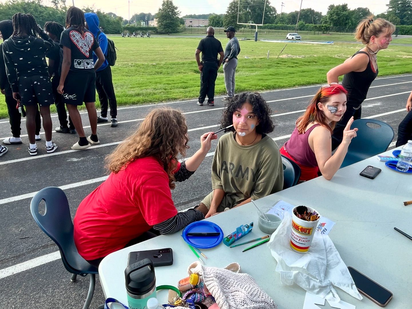 2 JROTC students participating in face painting on the track.