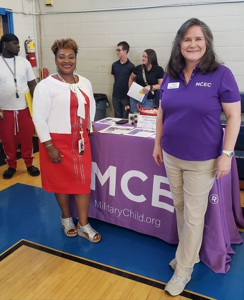 Mrs. Kimberly WIlliams and Other Woman in front of the military child table wearing read white and purple.