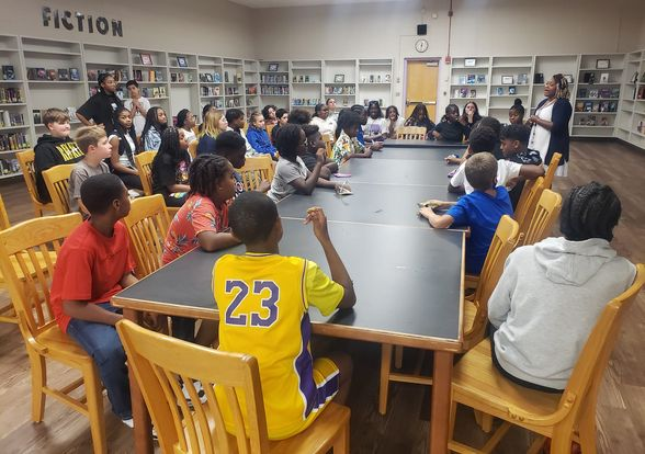 ASFL Midldle School Students seating in the library listening to Mrs. Williams during a meeting.