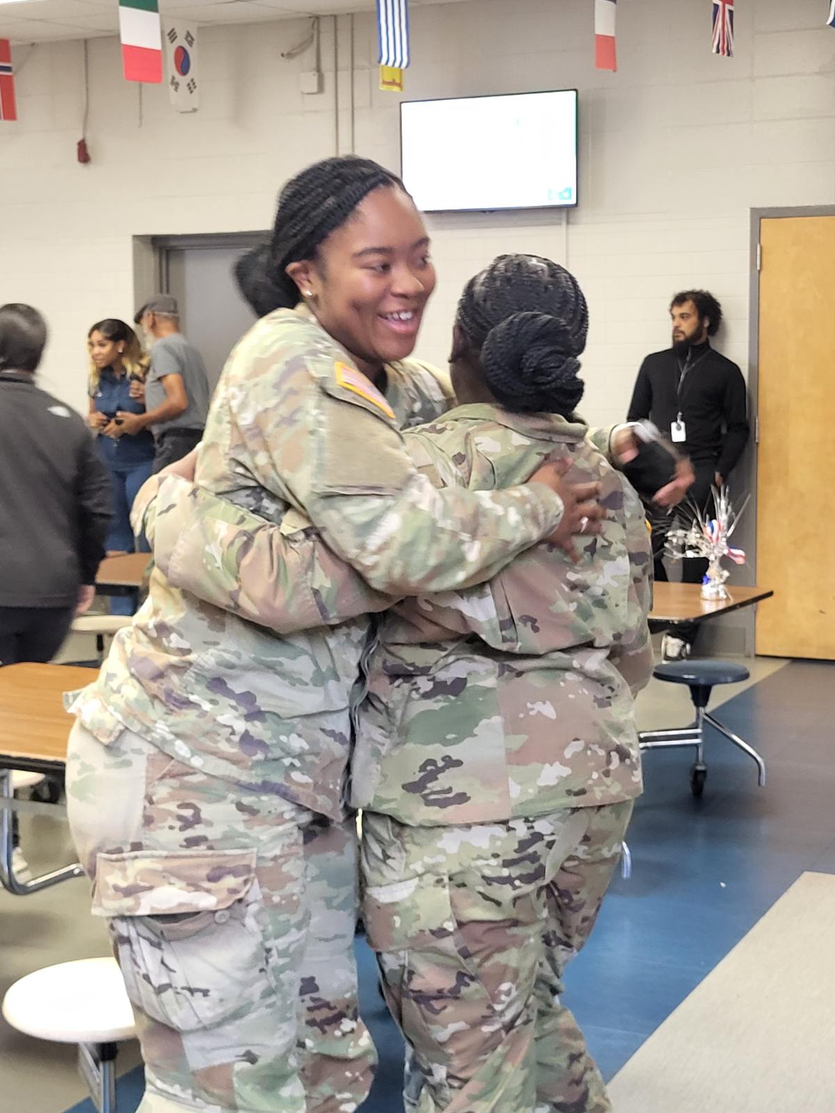 Two African American wowen soldiers in uniform hugging and smiling during Veterans Day at ASFL elementary