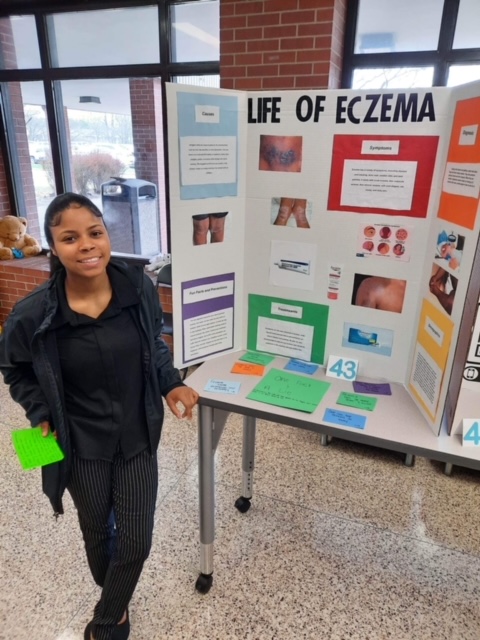 student in front of picture board display