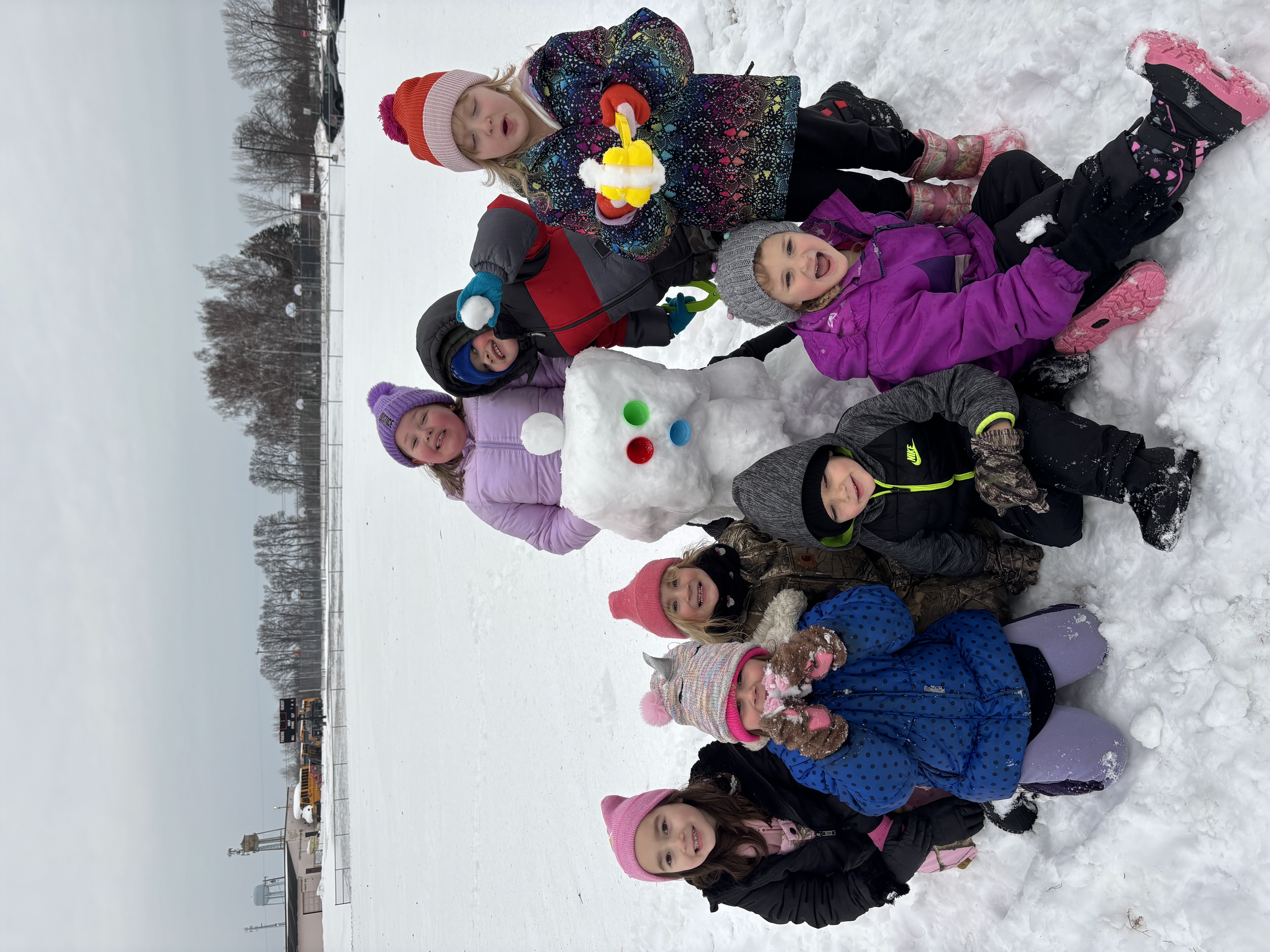 kids playing in snow near snowman