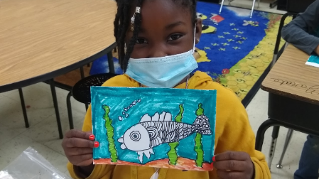 Student holding fish drawing