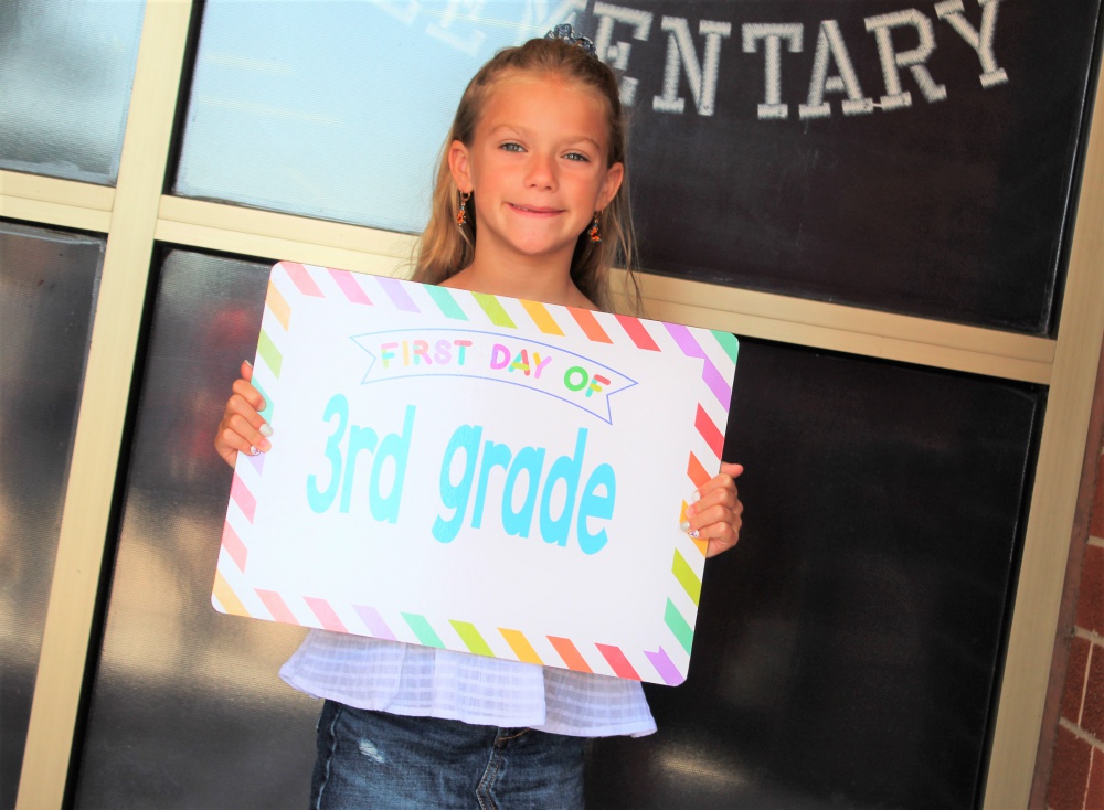 student showing sign to camera