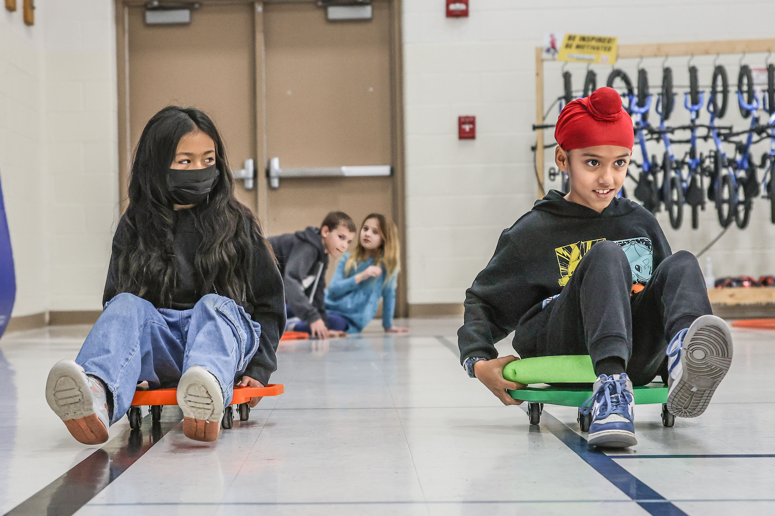 two students rolling toward camera on scooters
