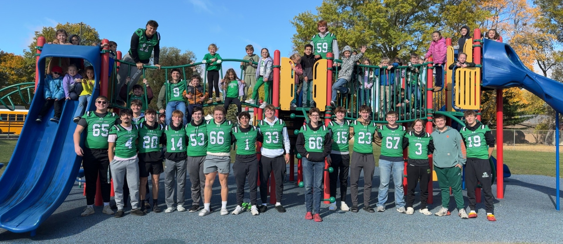 Football players and elementary students on playground equipment