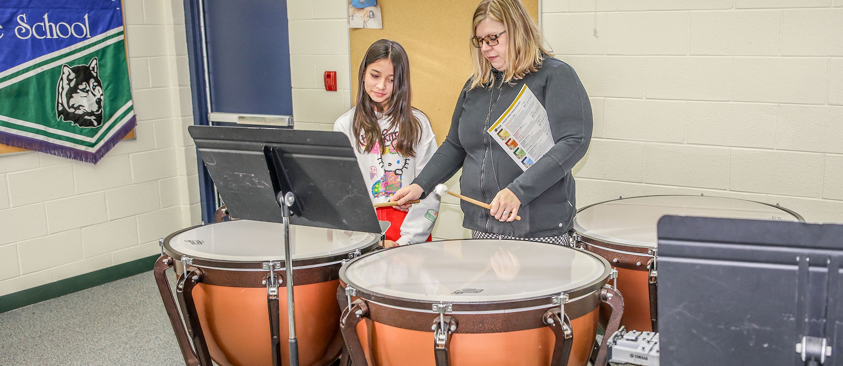 band director playing drum with student