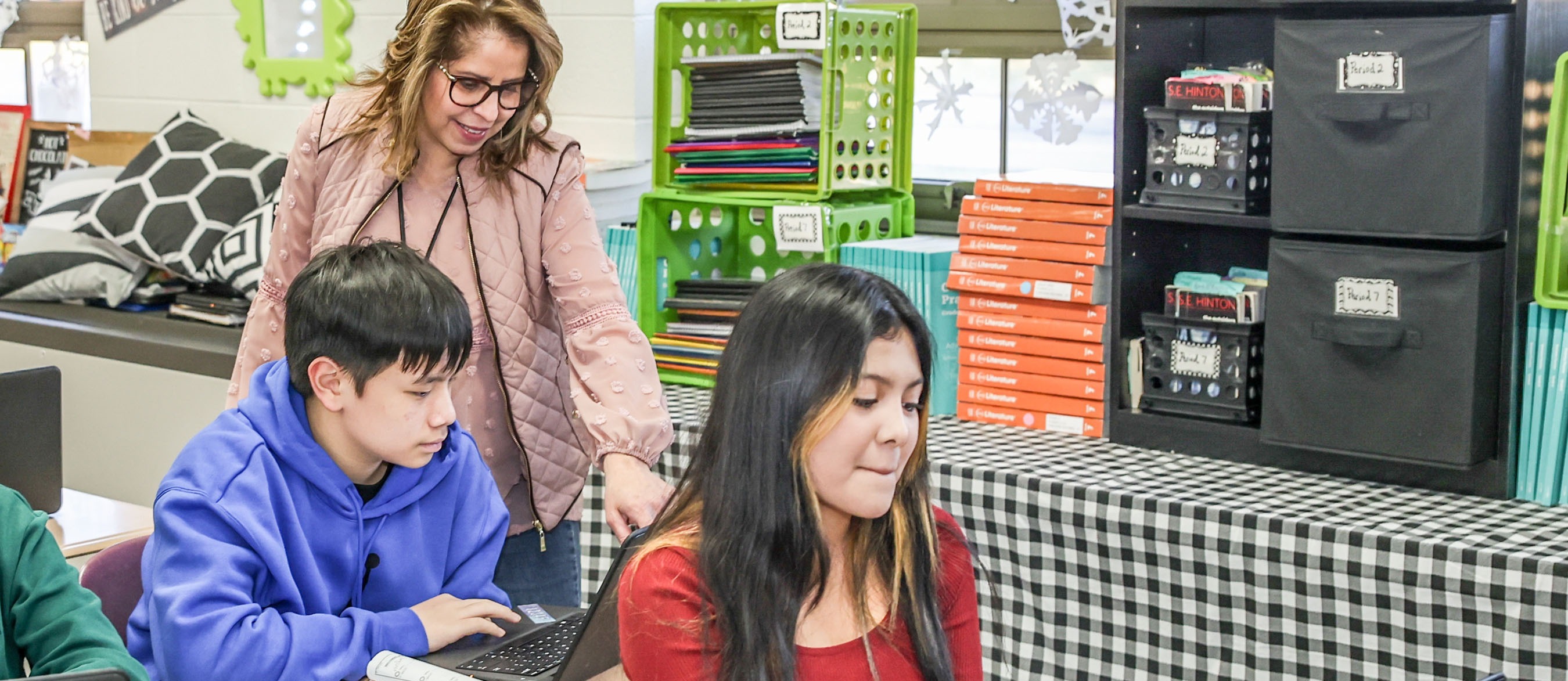 teachers stands behind students on computers