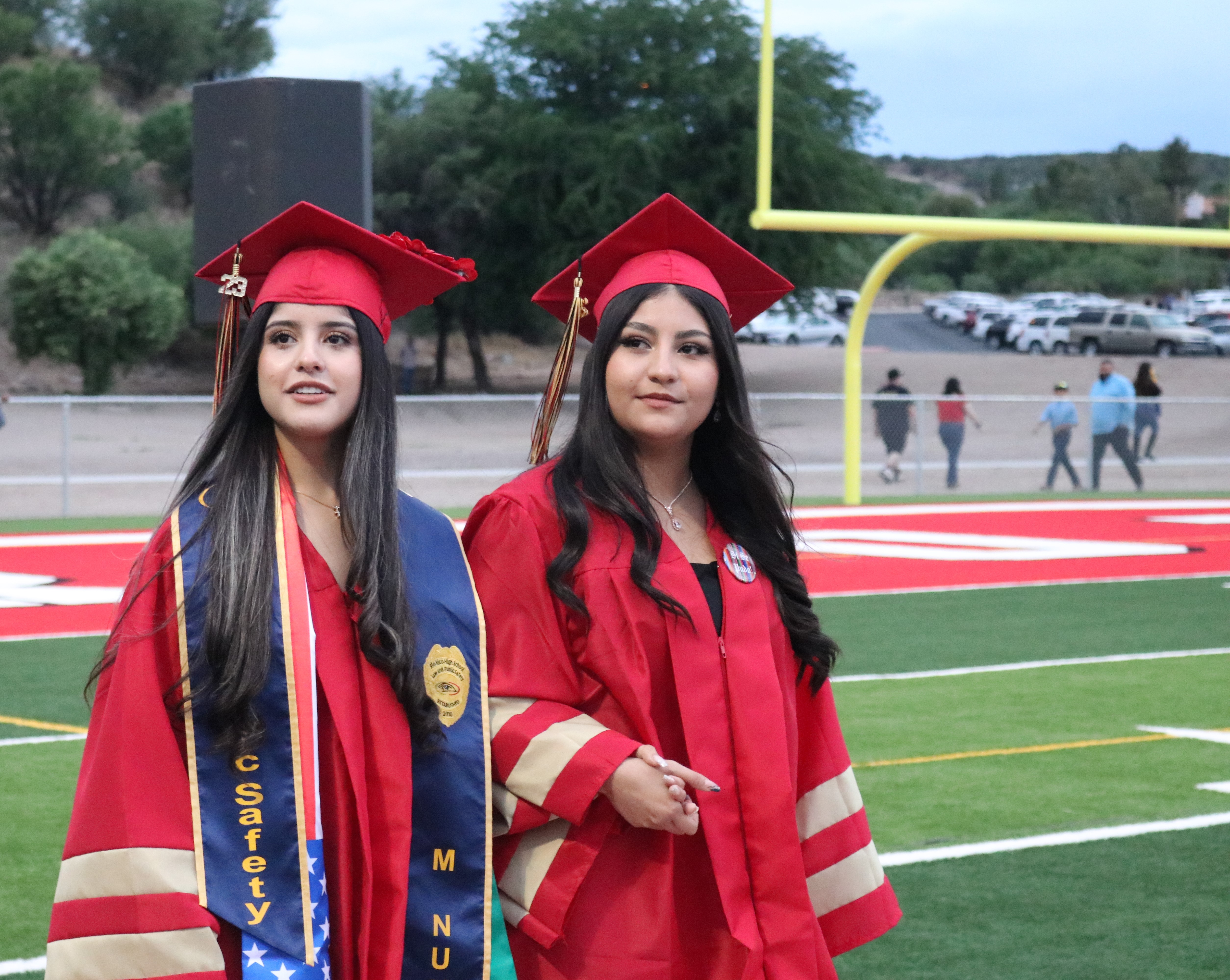Two seniors in cap and gowns walking the football field